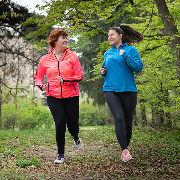 Mother and daughter wearing sportswear and running in forest