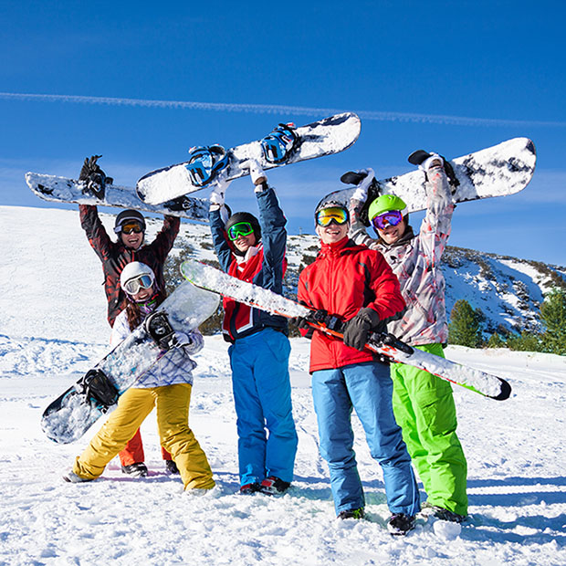 Five snowboarders holding oards and skies together